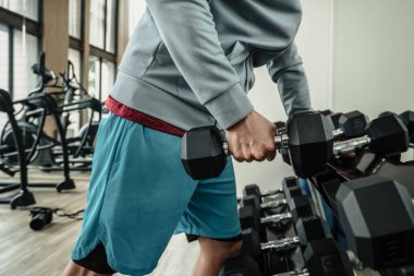 Spor salonunda halterle pazı egzersizi yapan bir adam. Fitness, egzersiz ve trans konsepti.
