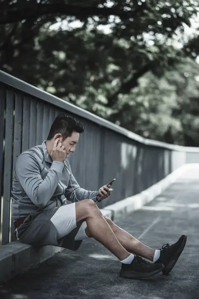 A man use smartphone Fitness application, social media, listening to music.  Health and Lifestyle in big city life concept.