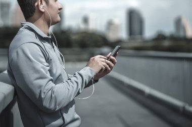 Spor adamı müzik kulaklığı dinle ve akıllı telefon fitness uygulaması kullan, sosyal medya, müzik dinle. Büyük şehir yaşam konseptinde sağlık ve yaşam tarzı.