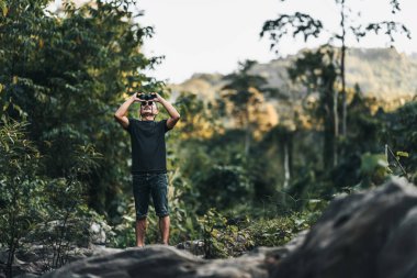 Yürüyüşçüler hayvanları görmek için dürbün kullanır ve ormanda sırt çantalı manzarayı görürler. yürüyüş ve macera konsepti.