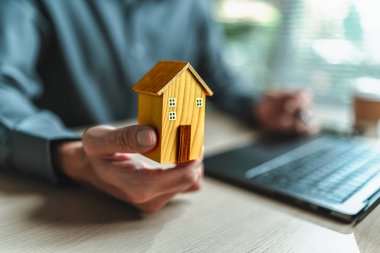 Ev satış elemanı, sigorta satıcısı elinde bir ev tutuyor. Varlıklar, gayrimenkul, krediler ve gayrimenkul kavramı.
