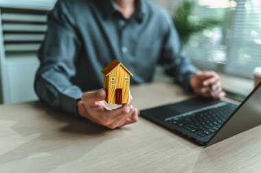 Ev satış elemanı, sigorta satıcısı elinde bir ev tutuyor. Varlıklar, gayrimenkul, krediler ve gayrimenkul kavramı.