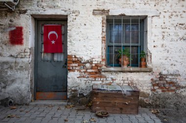 Kapısı olan eski bir ev ve Türkiye bayrağı boyalı bir pencere.