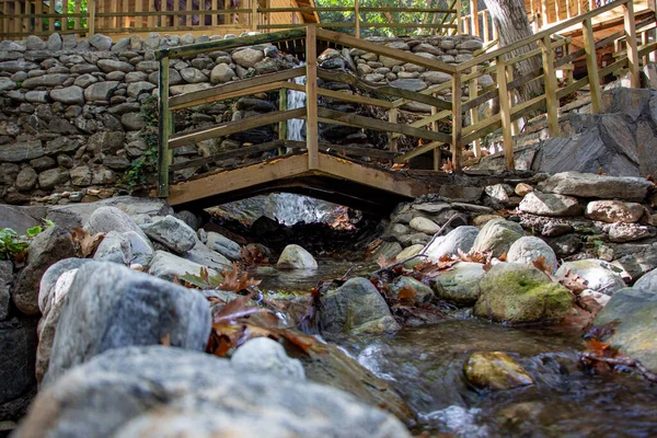 森の中の小さなストリーム上の木製の橋 秋には岩や葉で庭の滝 田舎の家の庭の小川にかかる木製の橋 — ストック写真