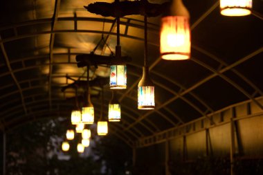 Parkın tavanında asılı duran klasik ampuller. Geceleri bir kafede tavandan sarkan lambalar..