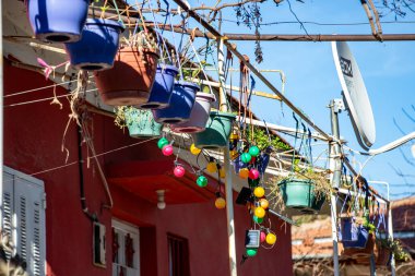 Caddedeki bir evin duvarında asılı renkli seramik kaplar. Evin balkonunda renkli seramik kaplar asılı..