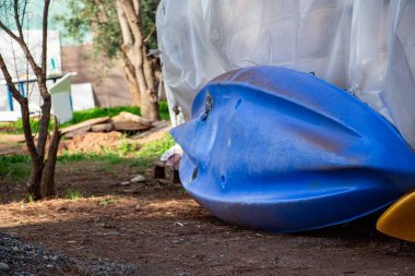 Terk edilmiş ahşap bir ev, Türkiye sahilinde kanoları var. Mavi ve sarı kano evin önünde yerde.