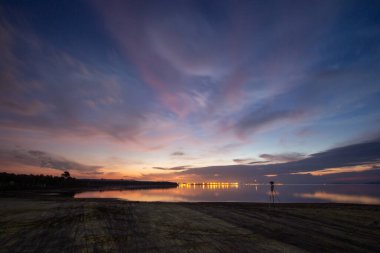Denizin üzerinde gün batımı dramatik gökyüzü ve suda yansıma. Akşamları gölde güzel bir günbatımı. Doğa bileşimi.
