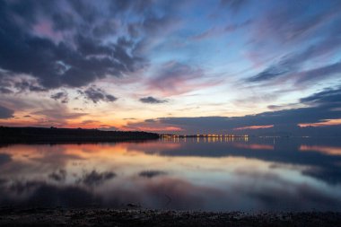 Denizin üzerinde gün batımı dramatik gökyüzü ve suda yansıma. Akşamları gölde güzel bir günbatımı. Doğa bileşimi.
