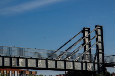 Modern bir köprünün çelik yapısının yakın görüntüsü. Caddedeki metal çitlere yakın çekim. Arka planda mavi gökyüzü olan çelik bir köprünün ayrıntıları.