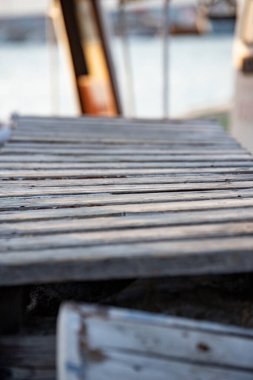 Denizin ve şehrin arka planında ahşap iskele. Bir gölün kıyısındaki ahşap iskelede kayalar ve mavi gökyüzü