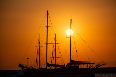Limanda gün batımında yatların silueti. Gün batımında denizde bir yelkenlinin silueti.