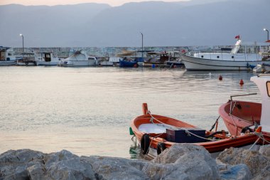 Limanda balıkçı tekneleri. Gün batımında körfezde tekneler. Limandaki kayalıklarda balık ağları.