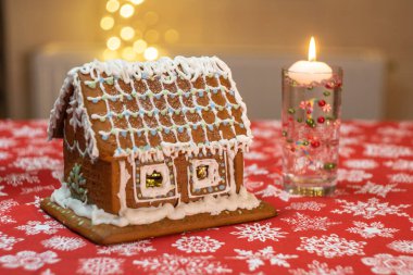 Masa örtüsü, süslemeleri, mumları ve fenerleri olan küçük zencefilli kurabiye evi. Işıklı oturma odası. Tatil havası. Yüksek kalite fotoğraf