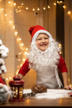 Noel Baba şapkalı mutlu çocuk Noel kurabiyesi yapıyor. Yüksek kalite fotoğraf