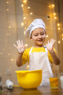 Cute toddler boy showing hands in flour at home. High quality photo