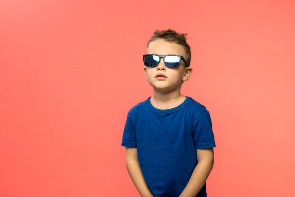 Boy in blue t-shirt with sunglasses isolated on pink background. Copy space. High quality photo