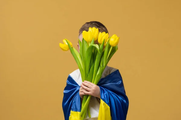 Little boy in yellow flower with flag of Ukraine on yellow background. High quality photo