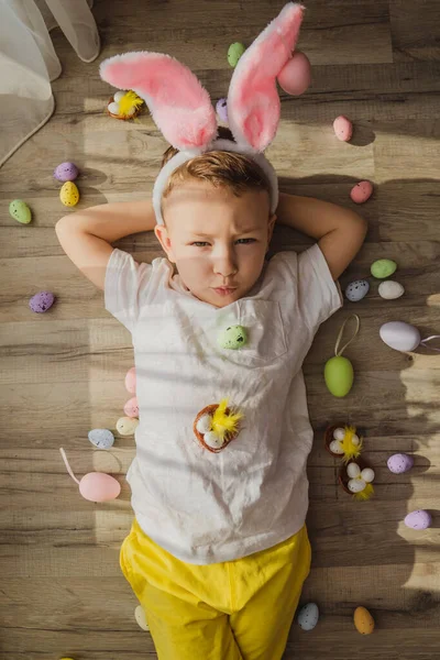 Счастливый Маленький Мальчик Кроличьими Ушами Лежит Деревянном Полу Красочными Яйцами — стоковое фото