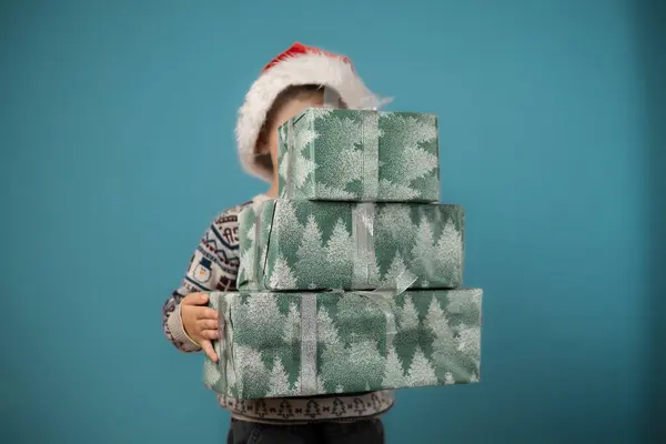 Noel Baba 'nın kırmızı şapkalı mutlu çocuğu Noel hediyelerini tutuyor. Noel zamanı. - Evet. Yüksek kalite fotoğraf