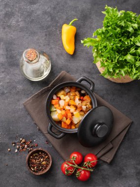 Kara arka planda taze marul, domates ve biberle siyah bir tencerede haşlanmış sebze karışımı. Diyet vejetaryen yiyecekler. Üst görünüm