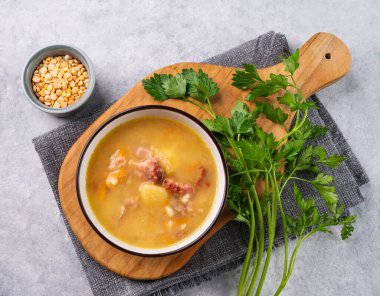 Tütsülenmiş jambonlu bezelye çorbası hafif arka planda bitki ile kesilmiş tahtada. Sağlıklı ev yemekleri. Üst görünüm.
