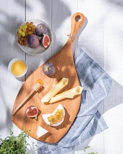 新鮮なハーブで白い背景に木の板の上にイチジク ブドウ 蜂蜜とチーズを盛り合わせ 朝食のための午前中に健康的でおいしい軽食 トップ表示 — ストック写真