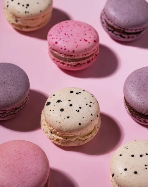 French sweet colorful macaroons on a pink background with a shadow. Flat  lay of concept delicious food. Top view