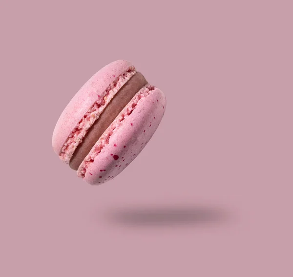 Fly french pink macaroon on a pink background. Concept levitation food. Copy space.