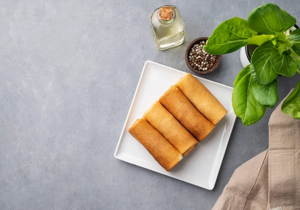 stock image Homemade roll crepes with meat on a plate on a blue  background with fresh herb, pepper and oil. Healthy food concept. Top view and copy space.