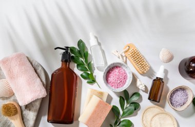 Deniz tuzu, sabun, sünger, fırça, losyon, deniz kabuğu, beyaz arka planda gölge palmiye yapraklı krem içeren yüz ve vücut bakım kozmetikleri kavramını uygulayın. Üst görünüm ve kopyalama alanı.