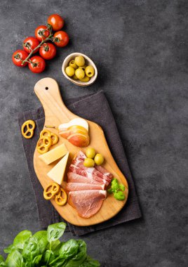 Çeşitli atıştırmalıklar ya da antipasti. Atıştırma tahtası. Jambonlu parmesan peyniri, zeytin, armut ve kraker, domatesli ve taze otlu. Üst görünüm ve kopyalama alanı.