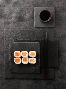 Somon, salatalık ve siyah tahta üzerine soya soslu sushi maki konsepti. Geleneksel Japon yemekleri. Üst görünüm.