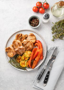 Izgara domuz eti, taze sebzeli biber ve kabaklı domates, baharatlı ve yağlı mavi bir arka planda. Üst görünüm ve  