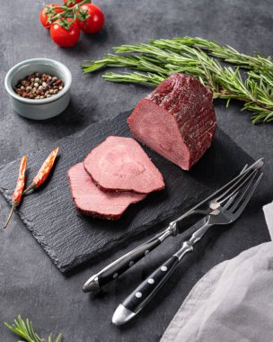 Sulu fırında biftek, domatesli, biberli ve koyu arkaplanda taze otlar.. 