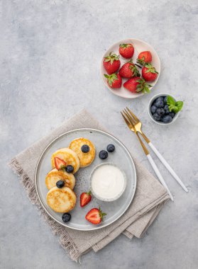 Peynirli kek ya da taze blerryli süzme peynir ve gri arka planda ekşi krema. Sağlıklı ve lezzetli kahvaltı kavramı. Üst görünüm ve kopyalama alanı.