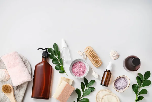 stock image Concept flat lay of facial and body care cosmetics with sea salt, soap, sponge, brush, lotion, seashells, cream on white  background. Top view and copy space.