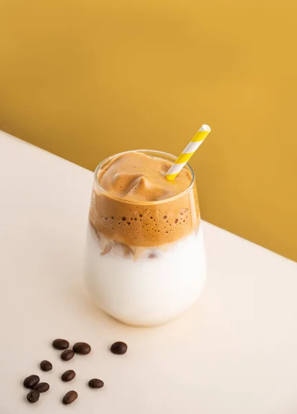 アイスキューブと黄色の背景に穀物とガラスの中に牛乳とダルゴナコーヒー 冷たい夏の飲み物の概念 トップ表示とコピースペース — ストック写真