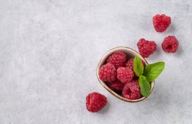 Nane yaprağıyla sulu orman ahududu hafif desenli arka planda bir kase. Sağlıklı gıda konsepti. Üst görünüm ve kopyalama alanı.