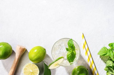 Limonlu mojito kokteyli, beyaz dokuda taze nane ve buz. Yaz ferahlatıcı narenciye içeceği. Üst görünüm ve kopyalama alanı.