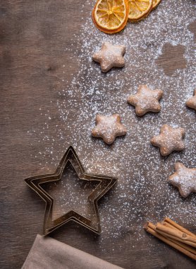 Düz kurabiye kesiciler, un, tarçın çubukları, portakal dilimleri, ahşap arka planda ev yapımı zencefilli kurabiyeler. Üst görünüm ve kopyalama alanı.
