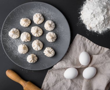Khinkali pişiriyorum. Un dolu bir tabakta etli el yapımı hamur tatlısı. Geleneksel Gürcü yemekleri. Üst görünüm