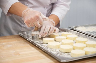 Bir kadın el yapımı cheesecake yapıyor. Yiyecek üretimi için fabrika. El yapımı iş.