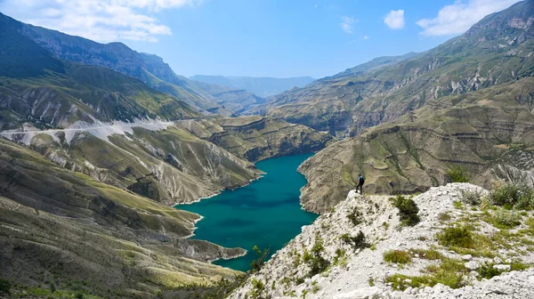 Bir turist bir dağda duruyor ve güneşli bir yaz gününde Sulak Kanyonu 'ndaki mavi-yeşil nehire bakıyor. Dağıstan, Rusya.