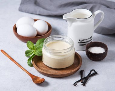 Lezzetli panna cotta ya da içinde malzemeler olan hafif bir arka planda kavanozda vanilyalı puding. Ev yapımı sağlıklı tatlı yiyecekler.