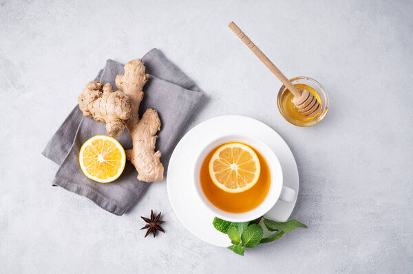 Чашка чая с лимоном, медом, мятой и имбирем на светлом фоне. Концепция здорового напитка для иммунитета. Вид сверху и место для текста.