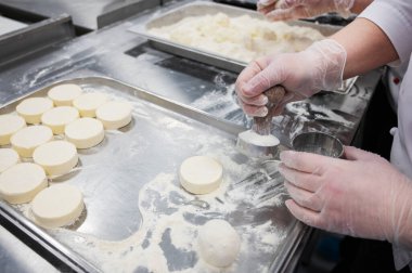Bir kadın el yapımı cheesecake yapıyor. Yiyecek üretimi için fabrika. El yapımı iş.