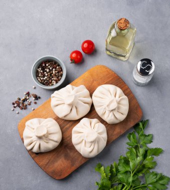 Mavi arka planda pişirilmemiş ahşap bir tahtanın üzerinde et, ot ve baharatlı Gürcü Khinkali hamur tatlısı. Üst görünüm ve kopyalama alanı.