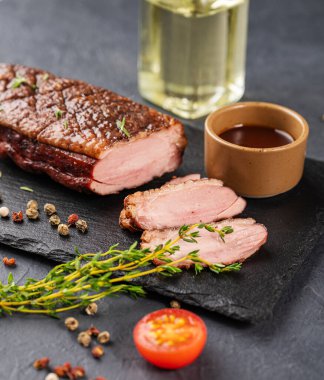 Salamurada ızgara barbekü ördeği göğsü ve kaplama tahtada soslu baharatlar ve koyu bir arka planda taze otlar. Sağlıklı diyet yemekleri.