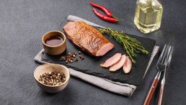 Salamura soslu ızgara barbekü ördeği pastırması ve kaykay tahtasında sos ve koyu arkaplanda taze otlar. Sağlıklı diyet yemekleri. Metin için boş alan.